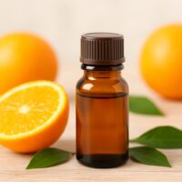 柑橘系のオレンジの果実と精油瓶が並んだ写真。アロマテラピーに使われるオレンジ精油のイメージ。